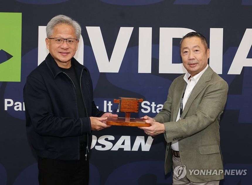 박정원 두산그룹 회장(오른쪽)이 7일 서울 잠실야구장을 방문한 젠슨 황 엔비디아 CEO에게 두산을 상징하는 조형물인 두산일두를 기념품으로 전달하고 있다.