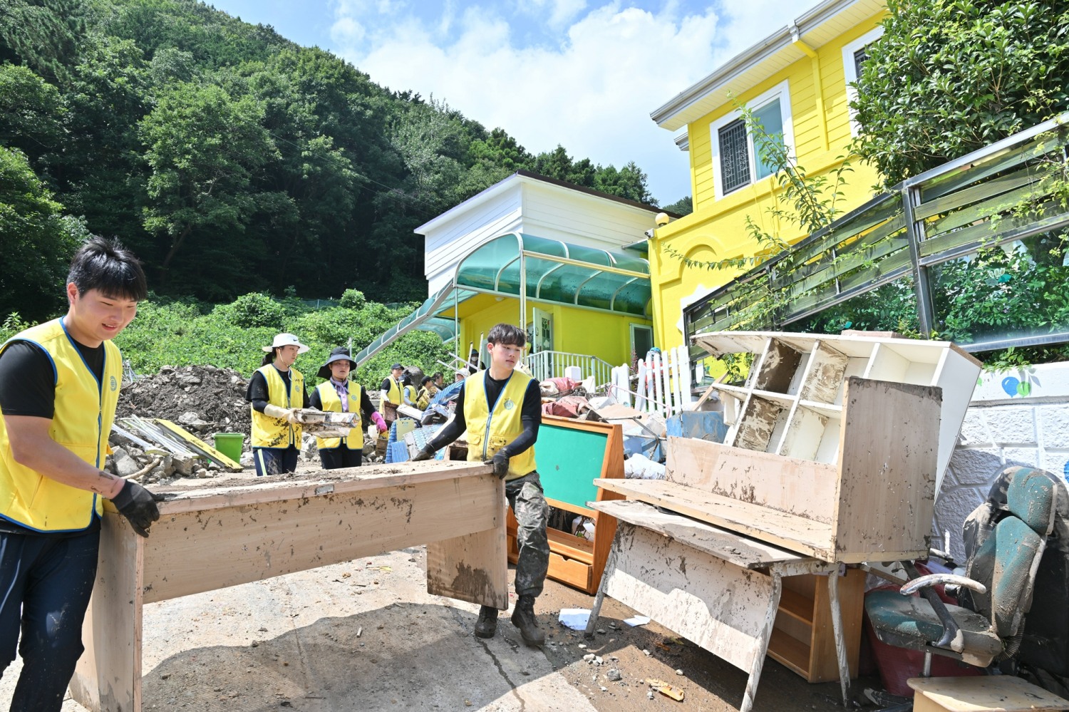 집중호우로 산사태 피해를 입은 거제시 옥포동의 어린이집에서 20일 하나님의 교회 봉사자들이 파손된 집기를 바깥으로 옮기고 있다.