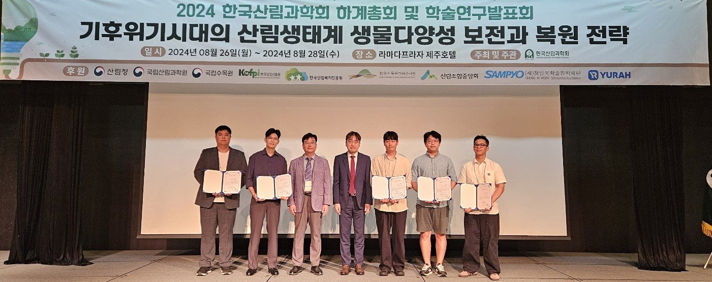 유용재 정인욱학술장학재단 사무국장(사진 가운데)과 이상현 한국산림과학회장(사진 왼쪽에서 세번째), 산림 Pioneer 육성 장학생 3기 5명이 지난 27일 라마다프라자 제주호텔에서 열린 장학증서 전달식에서 기념촬영을 하고 있다. (사진 제공=정인욱학술장학재단)