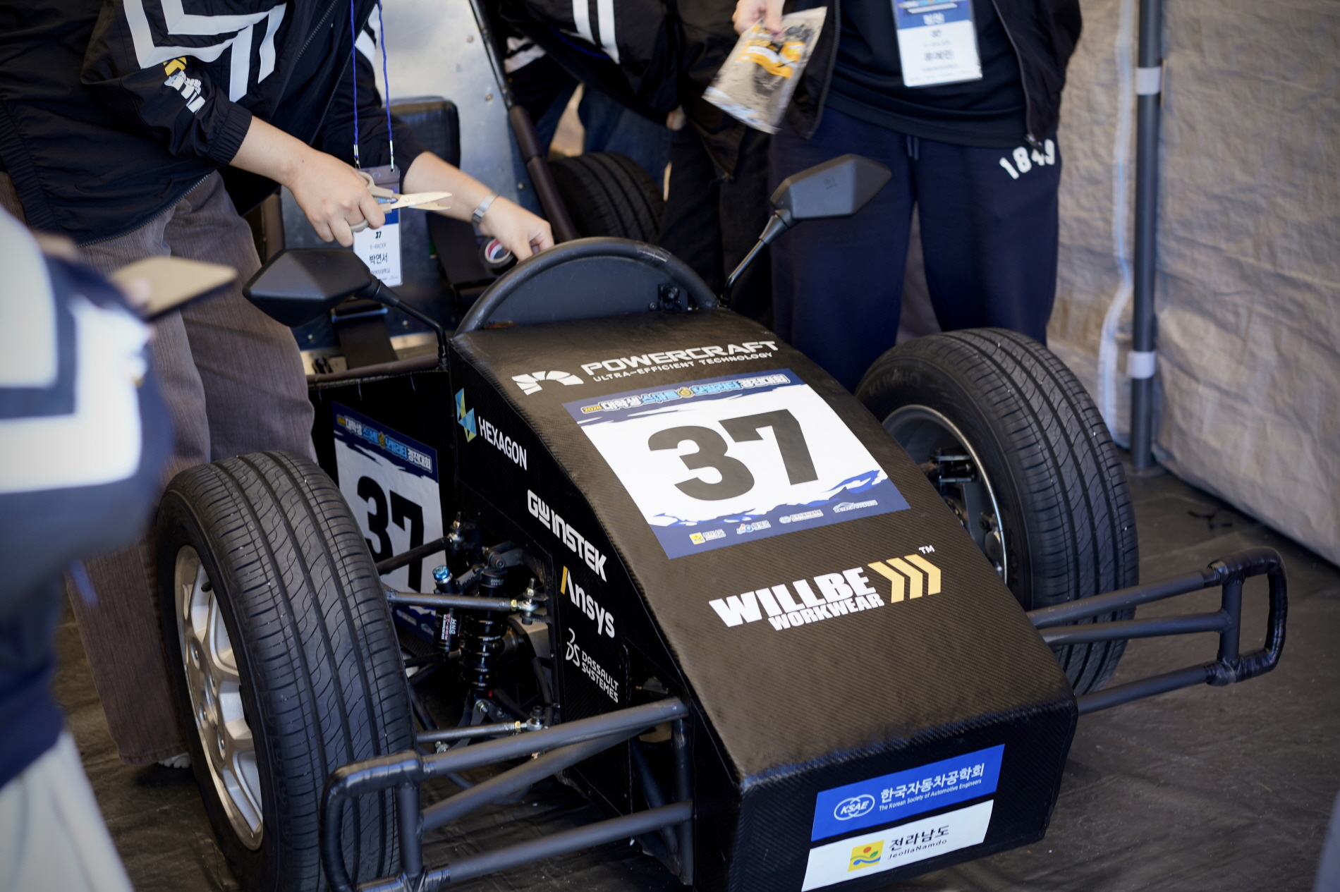 형지엘리트의 워크웨어 브랜드 ‘월비워크웨어’가 ‘2024 대학생 스마트 e-모빌리티 경진대회’에 출전한 이화여자대학교 자작차 동아리 ‘이레이서’에 단체복을 후원했다. 사진은 윌비워크웨어 로고를 부착하고 대회에 나선 이레이서의 자작차 모습