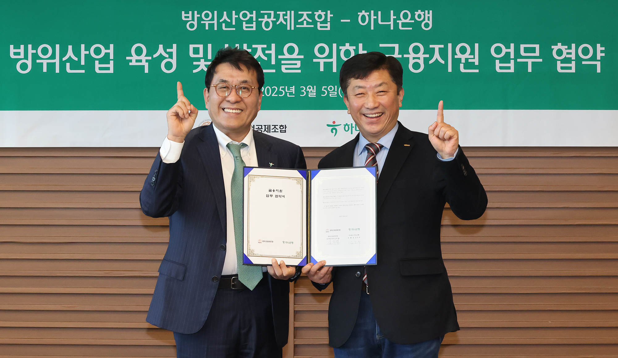 하나은행은 5일 방위산업공제조합과 K-방위산업의 육성 및 금융 지원을 위한 업무협약을 체결했다. 이날 협약식에 참석한 김진우 하나은행 중앙영업그룹 부행장(사진 왼쪽)이 김희철 방위산업공제조합 상근부이사장(사진 오른쪽)과 협약서를 들고 기념촬영을 하고 있다.