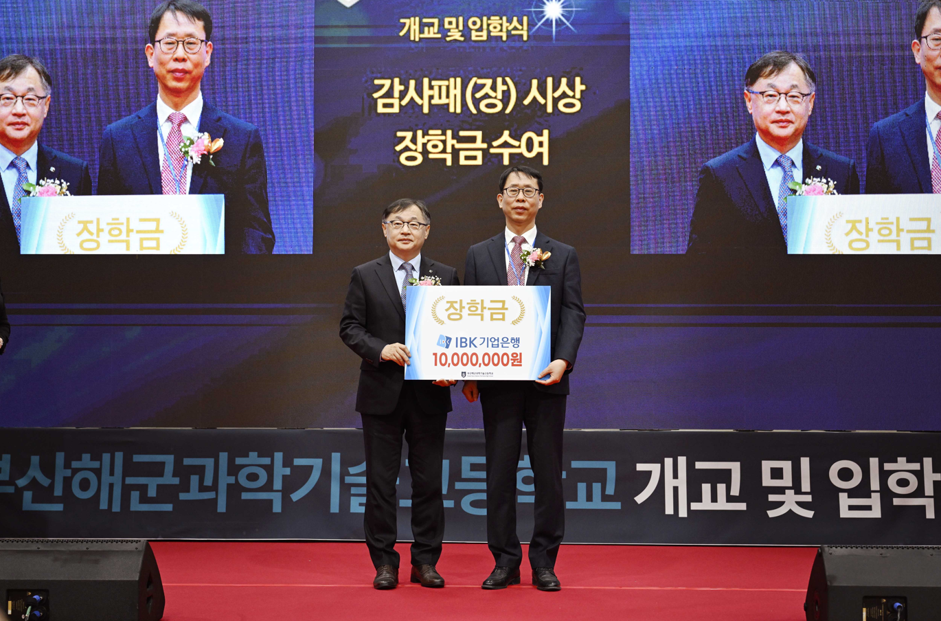 <사진은 지난 4일 부산해군과학기술고등학교에서 열린 개교식에서 유일광 IBK기업은행 개인고객그룹 부행장(왼쪽)이 정인식 부산해군과학기술고등학교 교장(오른쪽)에게 장학금을 전달하고 기념촬영을 하고 있는 모습>