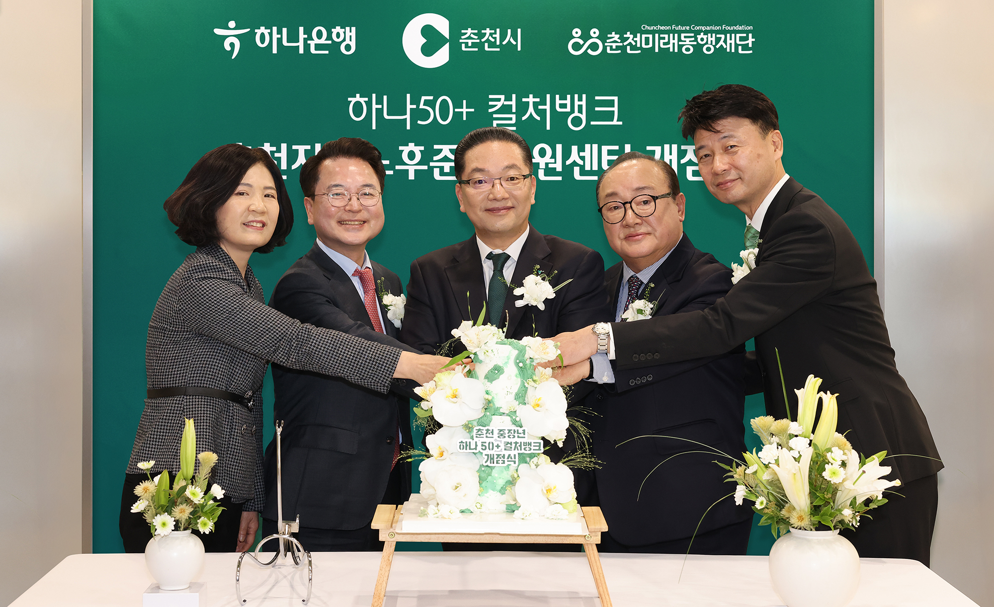 이날 개점식에 참석한 이호성 하나은행장(사진 왼쪽에서 세 번째)과 육동한 춘천시장(사진 왼쪽에서 두 번째), 신용준 춘천미래동행재단 이사장(사진 왼쪽에서 네 번째), 배숙경 춘천시의회 부의장(사진 왼쪽에서 첫 번째), 박장석 하나은행 춘천지점장(사진 왼쪽에서 다섯번째)이 케이크 커팅을 하며 기념촬영을 하고 있다.