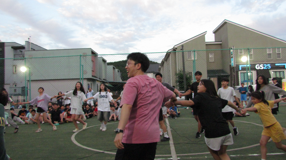 풋살장에서 열린 여름방학 캠프에서 아이들과 참가자들이 손을 잡고 원을 그리며 즐겁게 레크리에이션을 하고 있다./사진=HR그룹(주) 미디어팀 제공