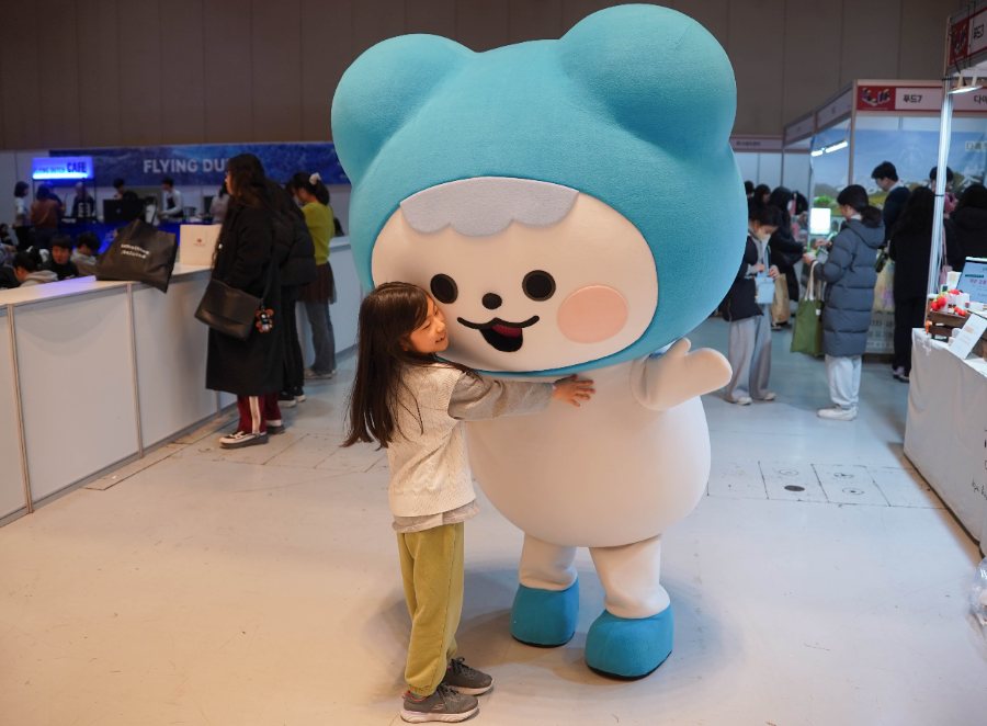 29일 서울 강남구 코엑스에서 열린 ‘K-일러스트레이션페어 서울 2026’을 방문한 관람객이 코이카의 소통 캐릭터 피코(PeKO)를 안아주고 있다.